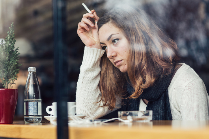 Young girl smoking and feeling depressed in a bar